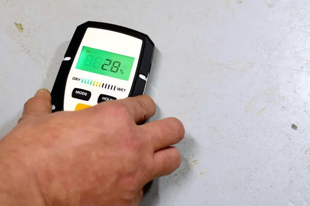 Technicien utilisant un appareil de mesure pour vérifier le taux d'humidité dans une dalle de béton